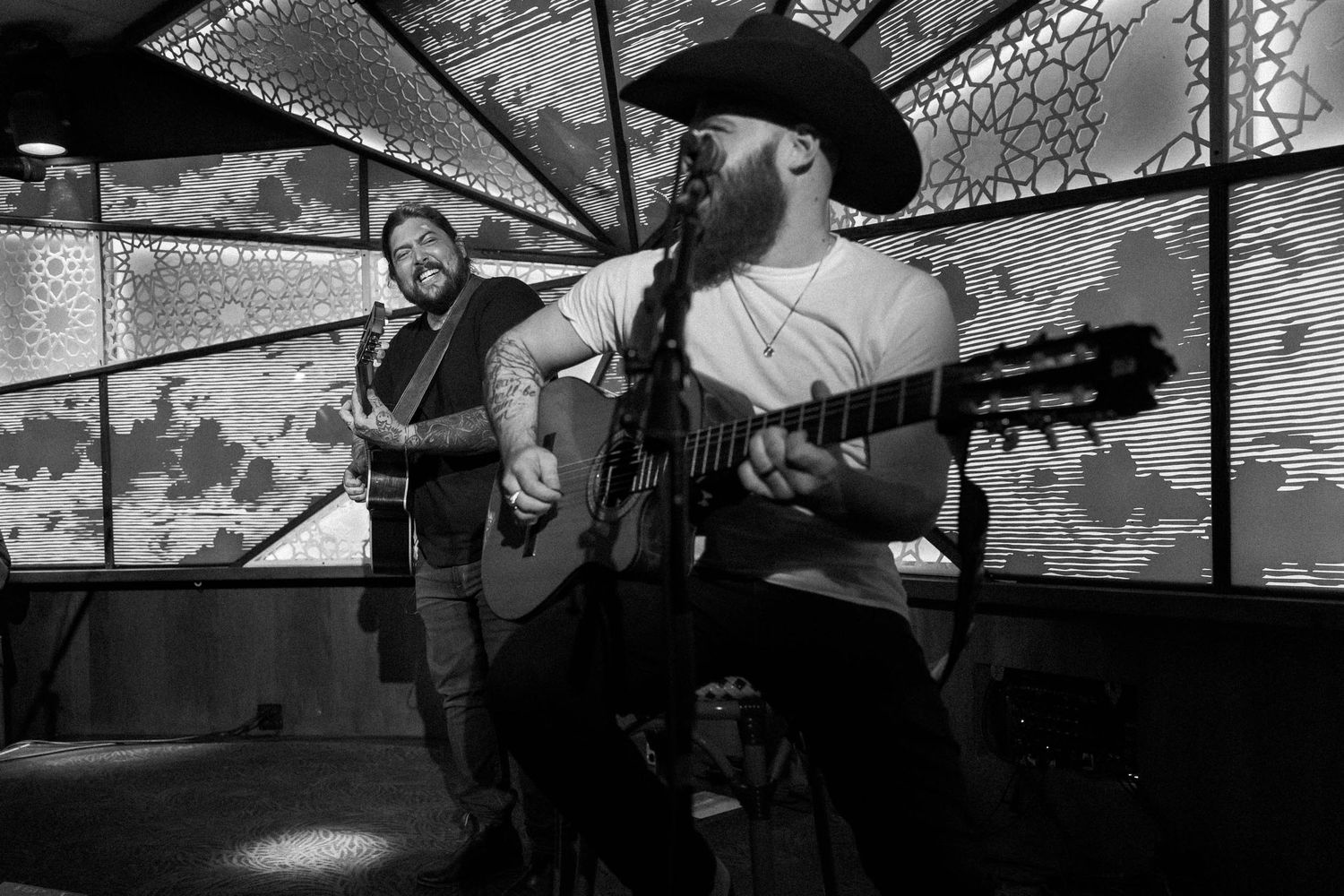 Black and white photo of musicians performing with artistic geometric patterns projected behind them.
