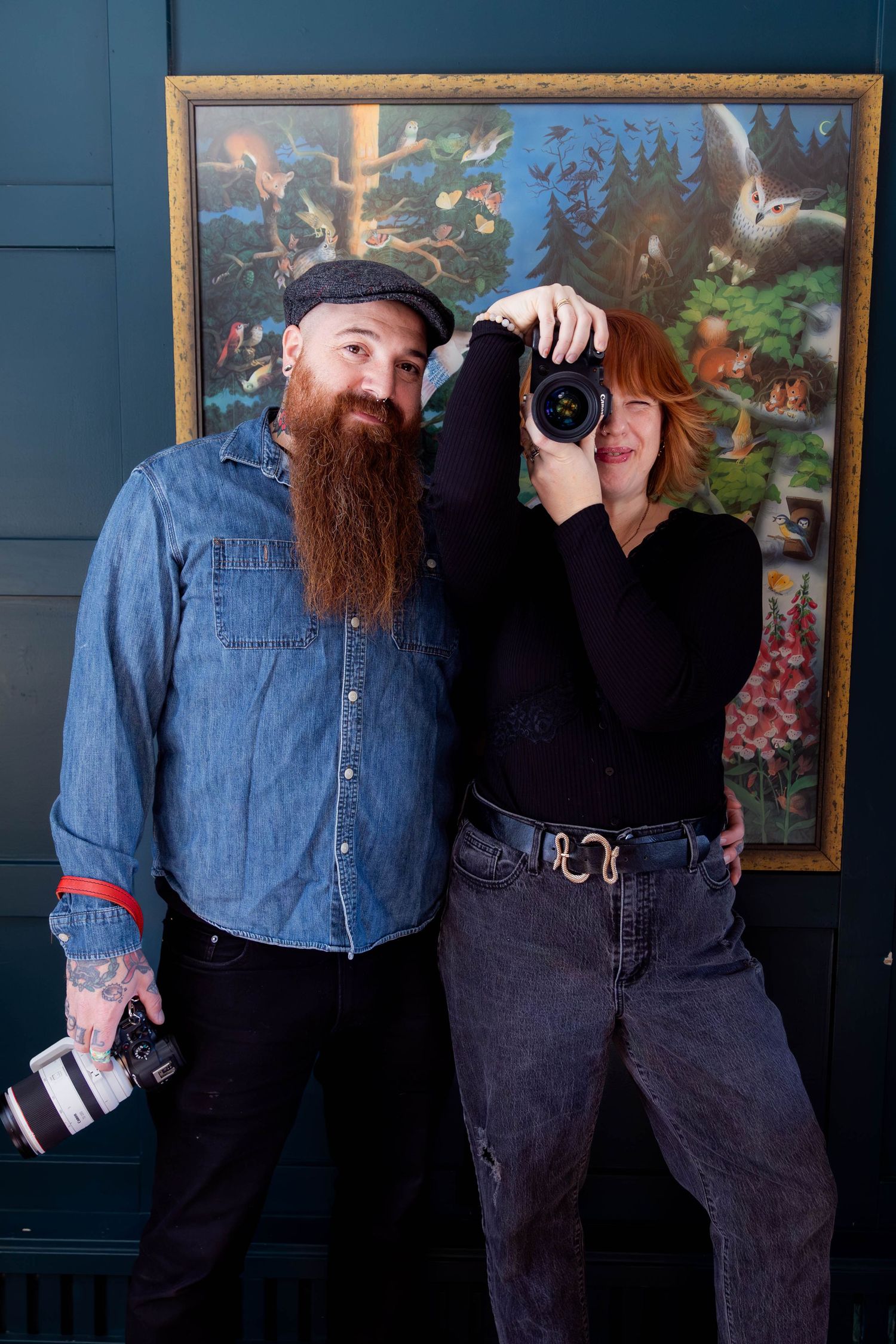 A couple in casual denim and black outfits pose together in a series of four candid shots against a dark wall.