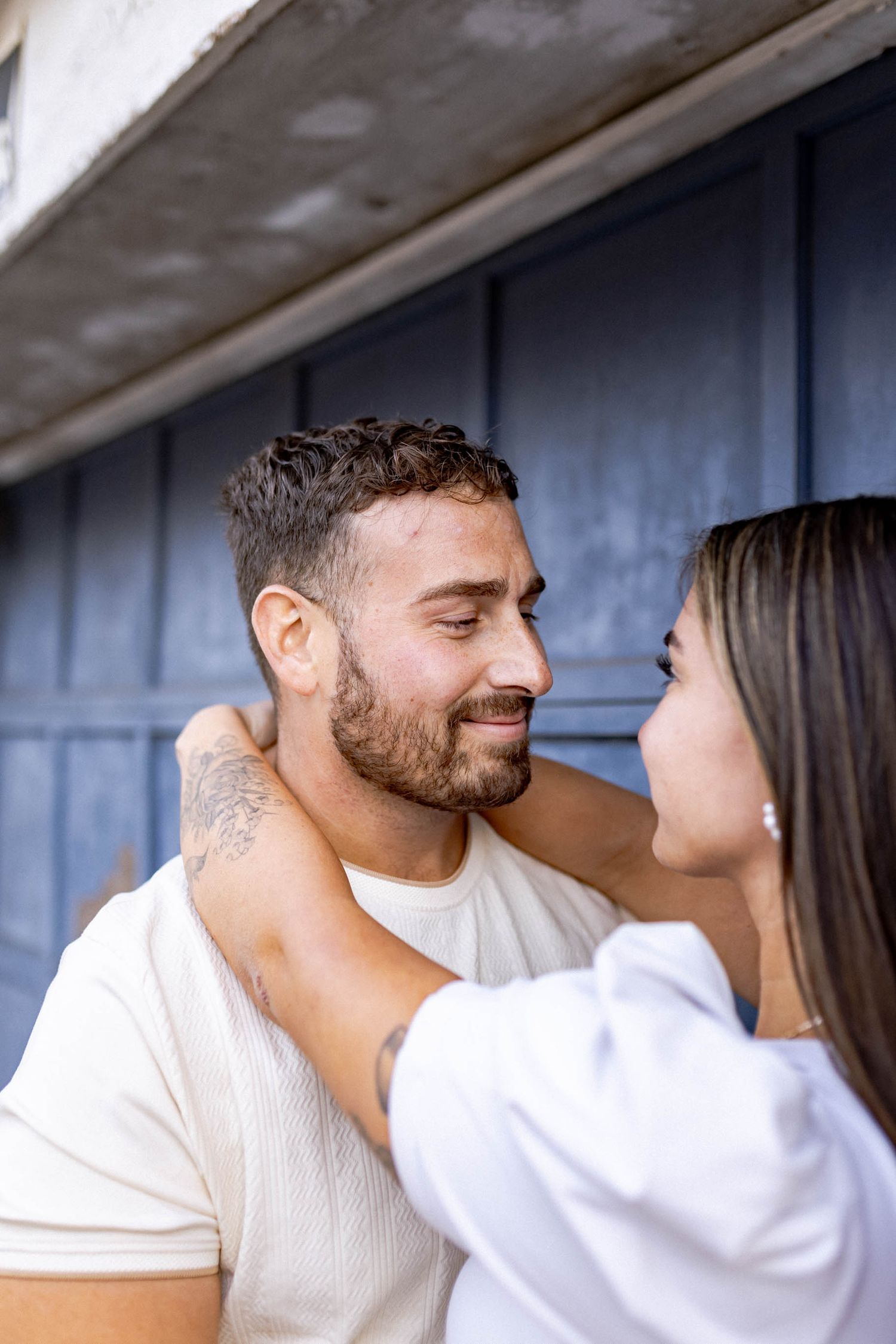 A couple in white clothing shares a tender moment while sitting together.