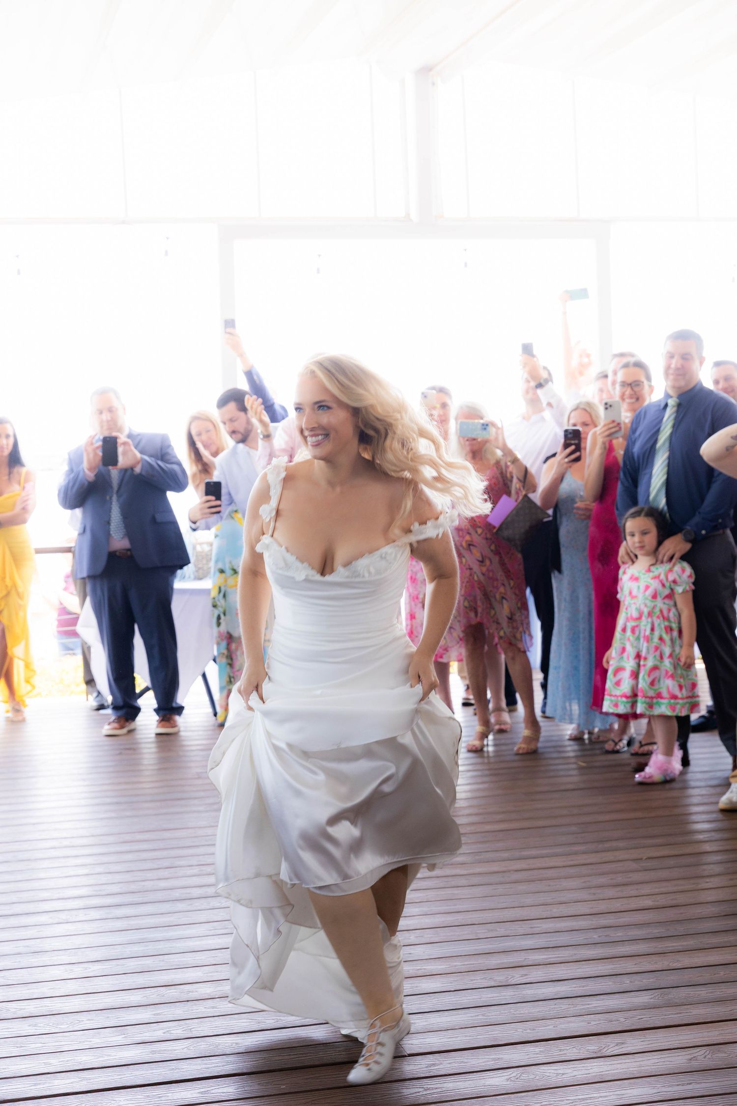 Sequence of photos showing a bride dancing energetically in a white dress on a wooden deck with guests in background.