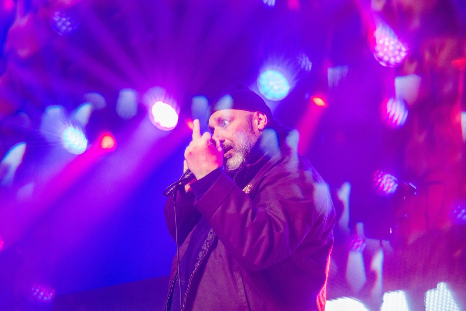 Concert performer on stage illuminated by vibrant purple and blue lighting during an energetic performance. Brooklyn Steel