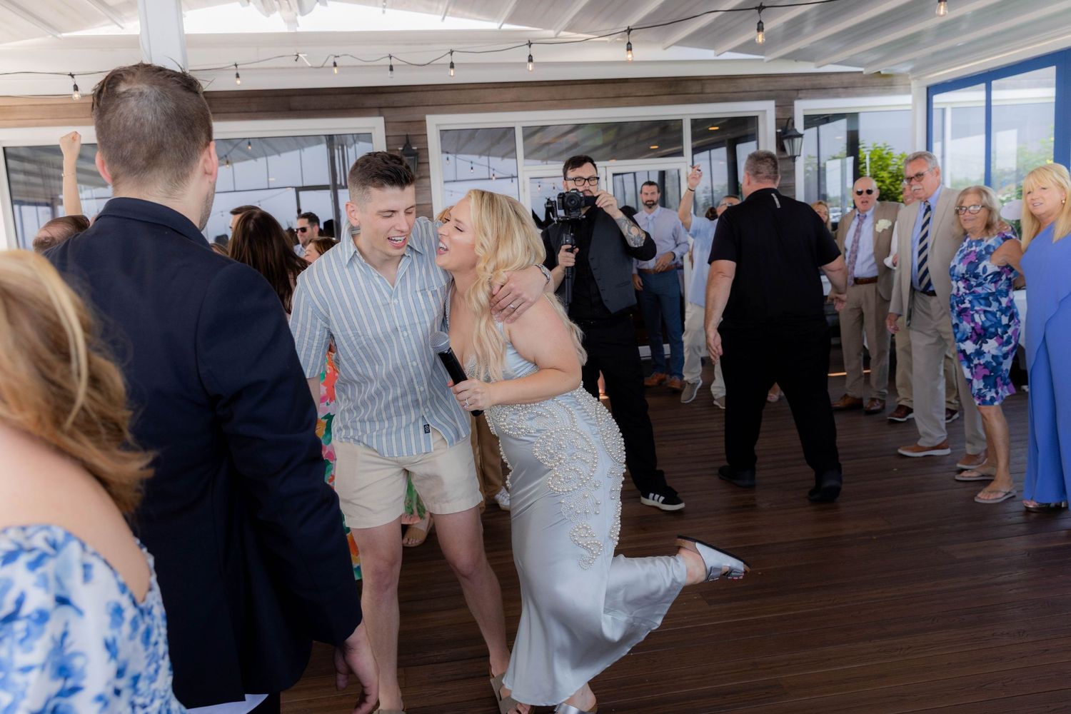 People mingling and socializing at an indoor event space with large windows and exposed ceiling beams.
