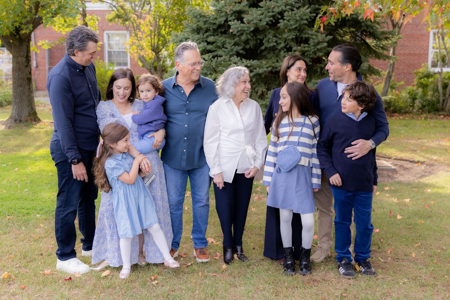 Extended family group poses together outdoors on grassy lawn during autumn. Fireside Sparrow Photography. Greenport, NY