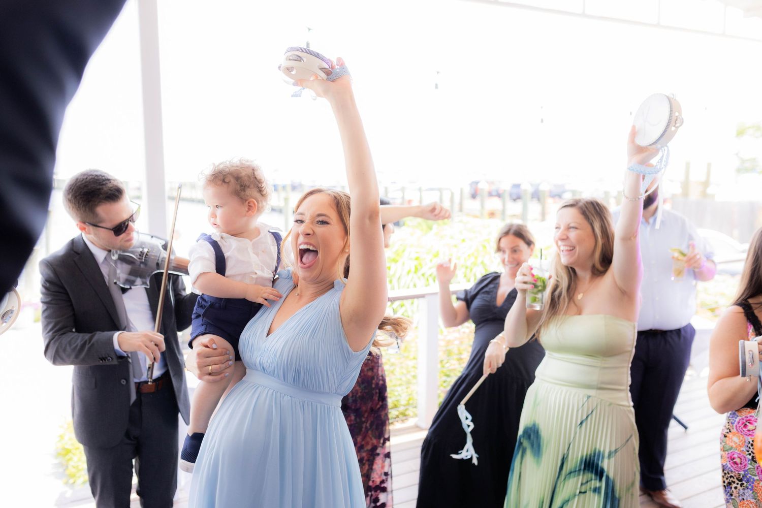 Wedding reception guests dancing and celebrating together on a dance floor with arms raised in joyful celebration.