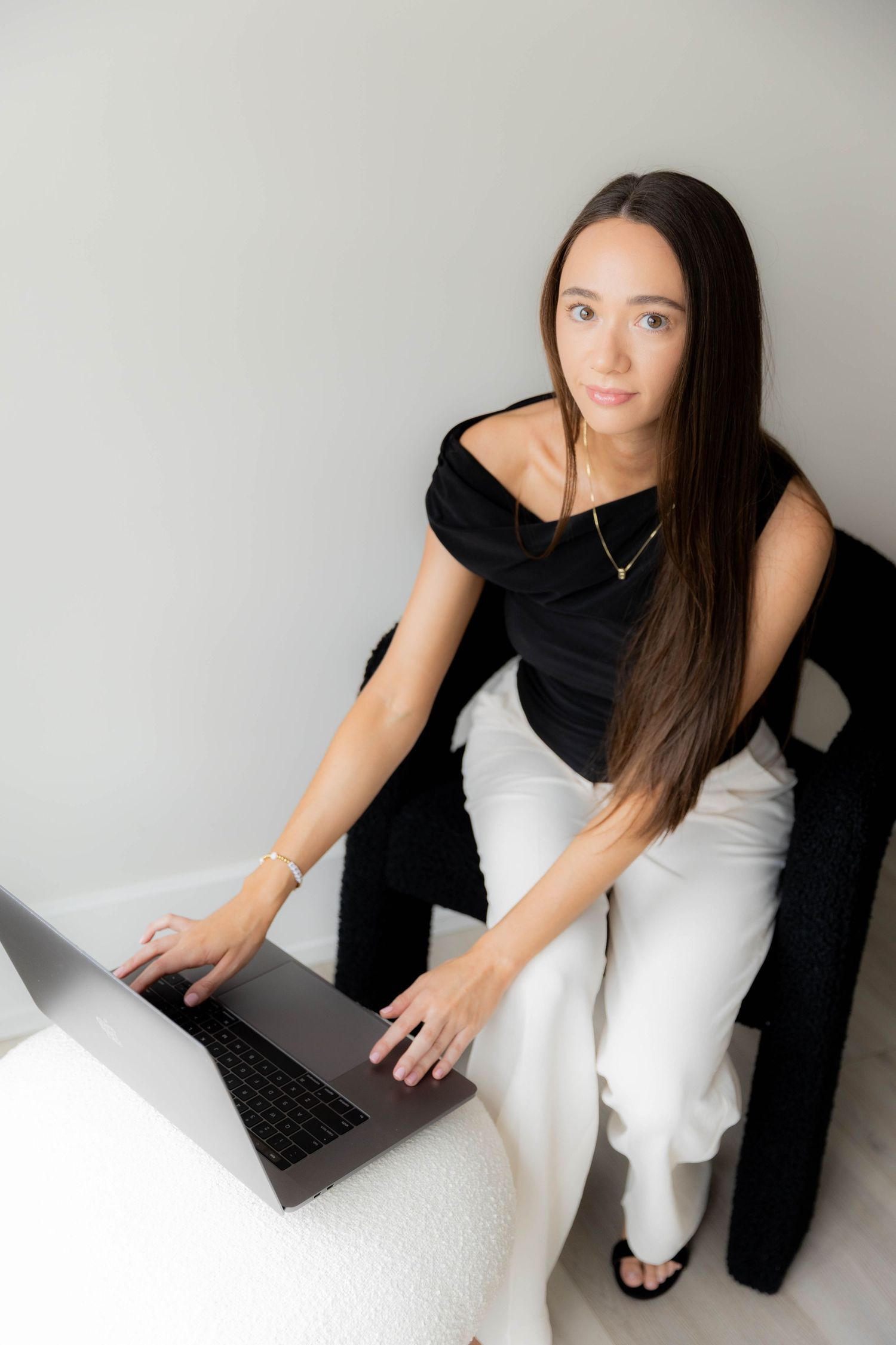 Professional working on laptop while seated in black and white business attire.