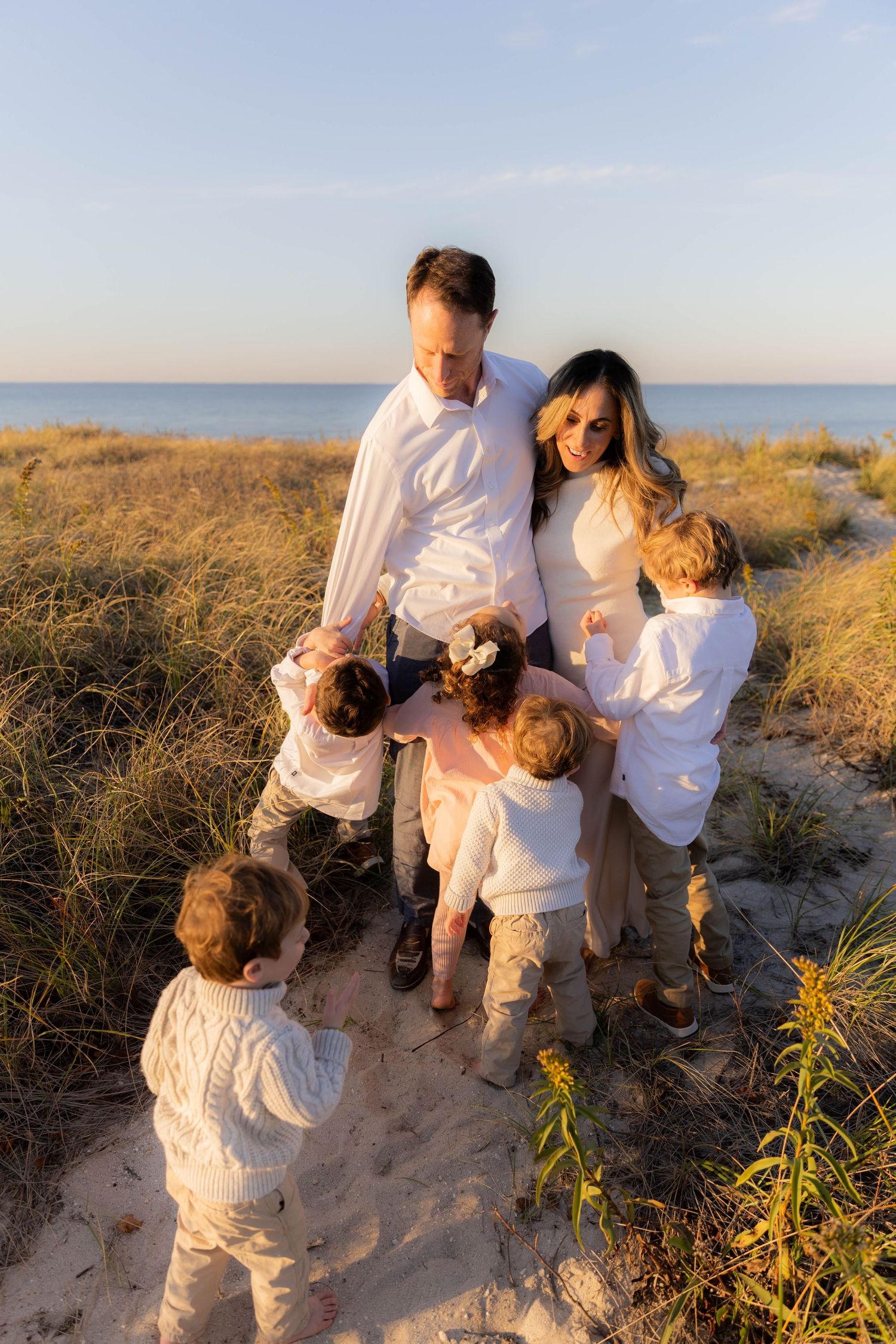 Happy family moment captured in golden light on coastal sand dunes.