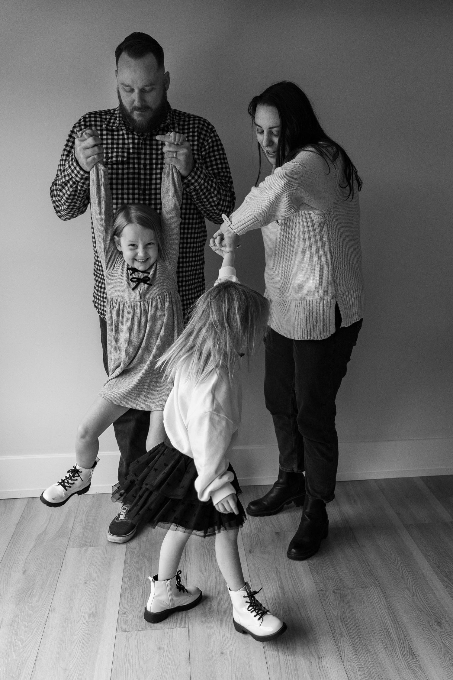 A black and white series of playful family interactions on a wooden floor. Huntington Loft, NY, Fireside Sparrow Photography