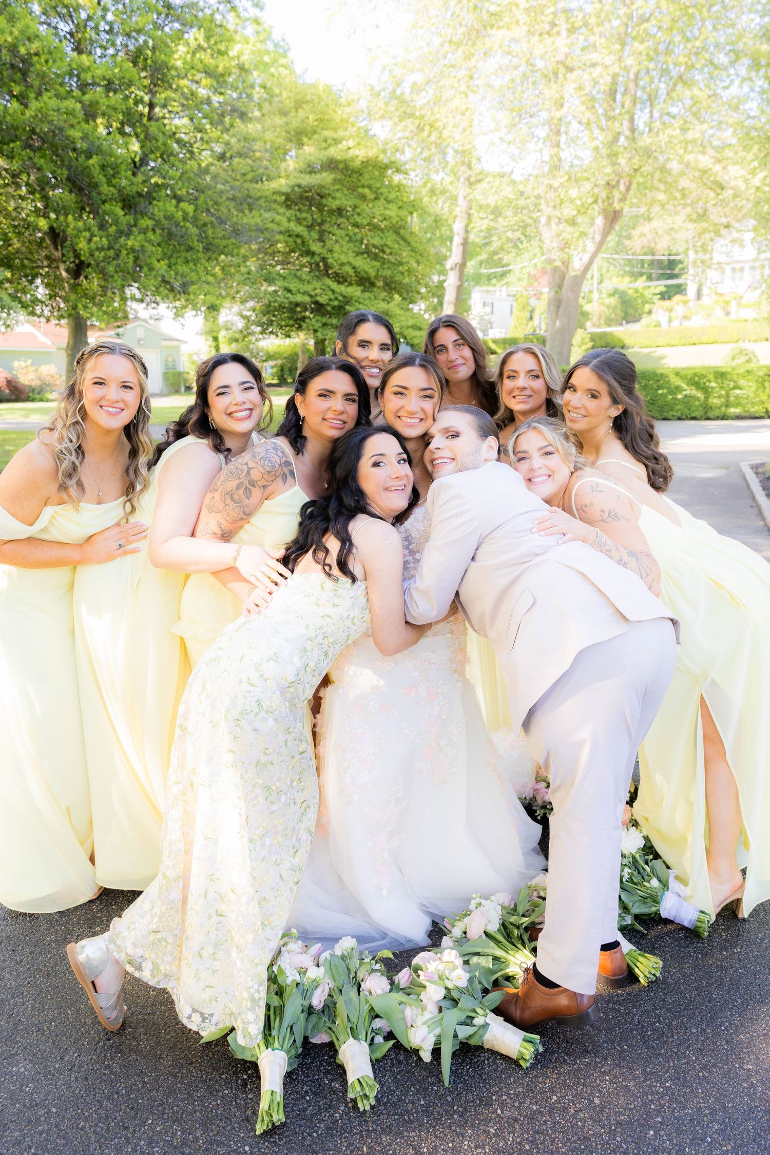 A wedding party in light yellow and white dresses poses together outdoors in a playful group photo series.