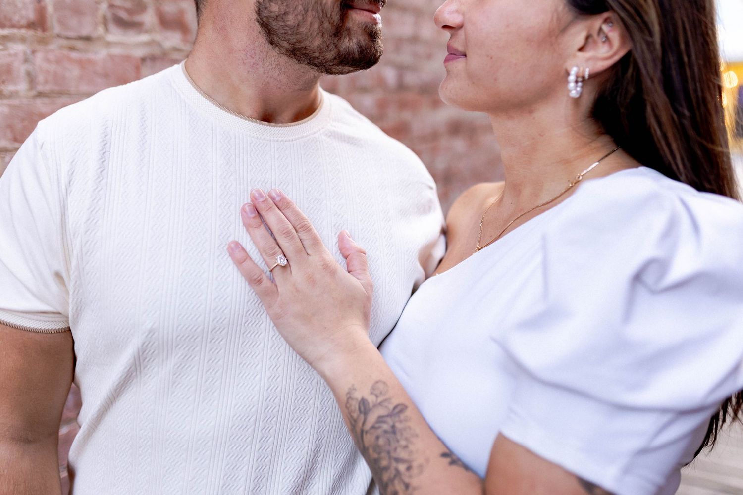 Couple in white t-shirts sharing intimate moments against a brick wall background.