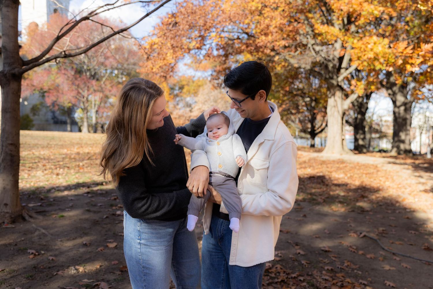 Family enjoying autumn day together on bench with fall colors in background.