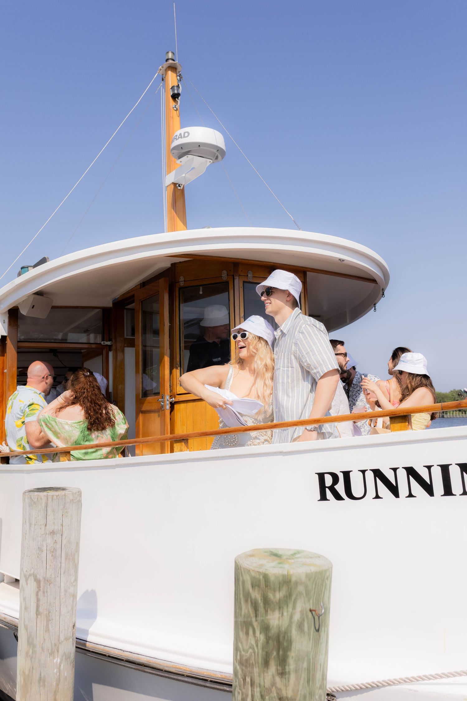 Passengers enjoying a boat trip aboard the vessel 'Running Wild' under bright blue skies.