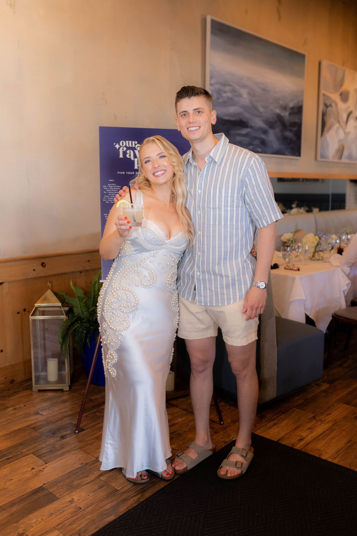 A couple dances together on a wooden floor during what appears to be a wedding reception.