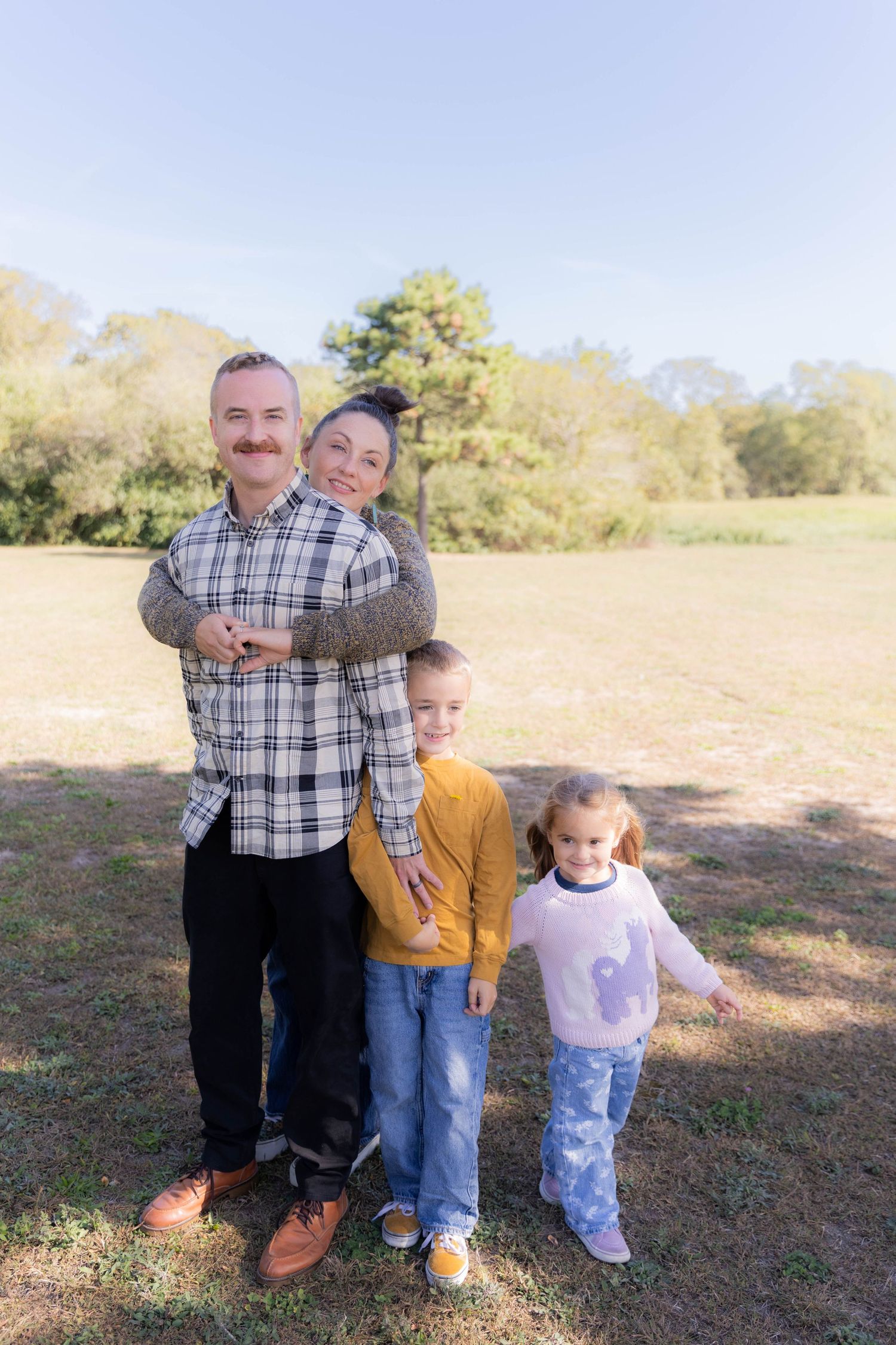 People gather for a casual outdoor photo session in a sunny field.