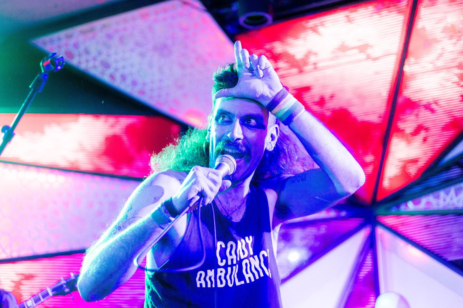 Close-up concert shot with vibrant pink and blue lighting effects.