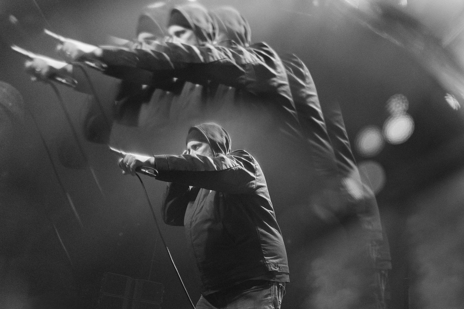 Black and white silhouette of performer in dramatic side lighting during stage performance.