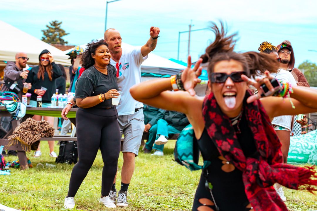 Crowd of people dancing and celebrating outdoors at a music festival on a sunny day.