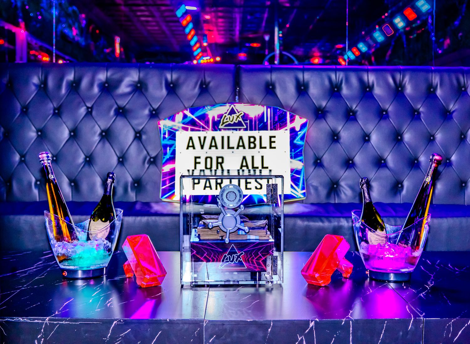 Luxurious nightclub VIP booth with tufted silver seating, champagne bottles, and neon 