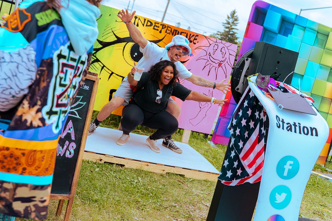 Woman crouching near colorful street art murals at an outdoor Independence Day community event with social media station.