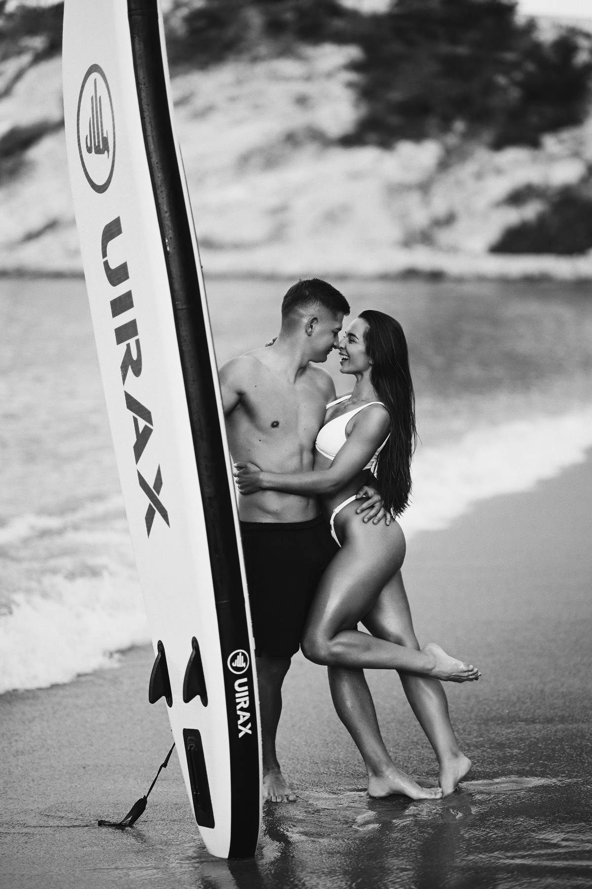 A couple stands with a paddleboard in the Mediterranean Sea, enjoying the serene coastal views of Moraira