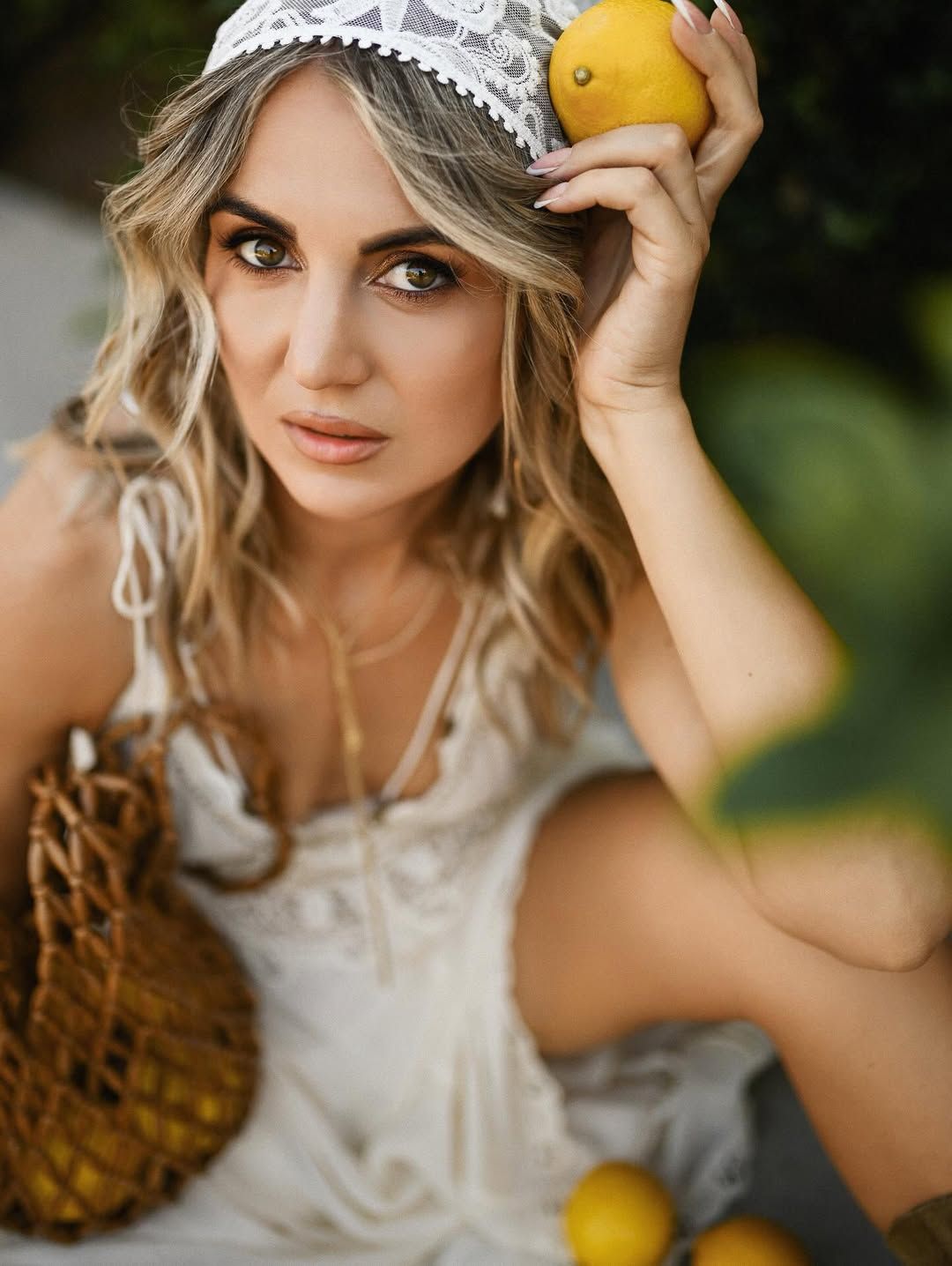 Woman in a white summer dress sitting by citrus trees in Jardín de Las Hespérides during a relaxed Valencia portrait session