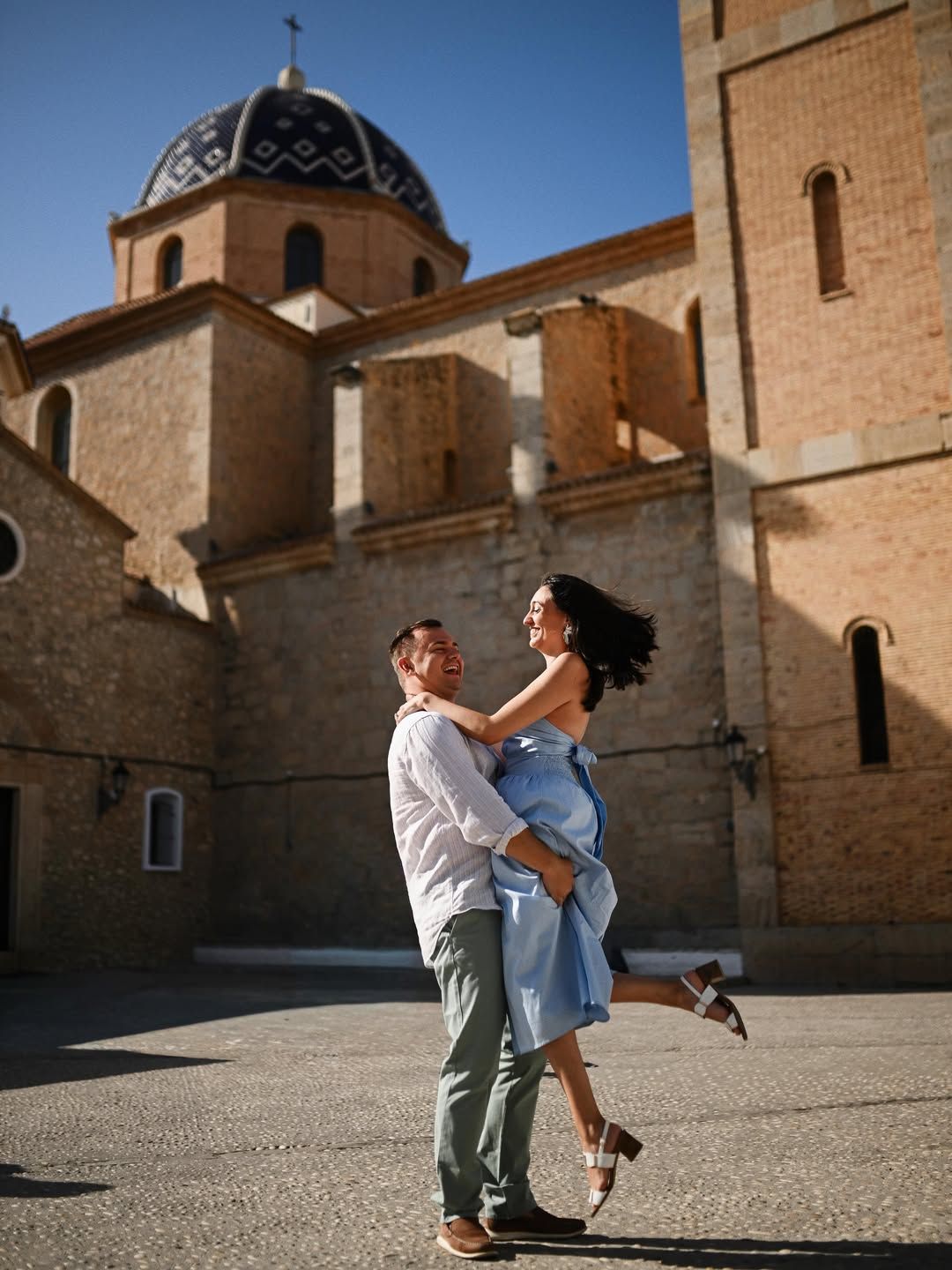 A happy couple celebrating their engagement in a historic spot in Valencia, Spain, with beautiful traditional architecture in the background