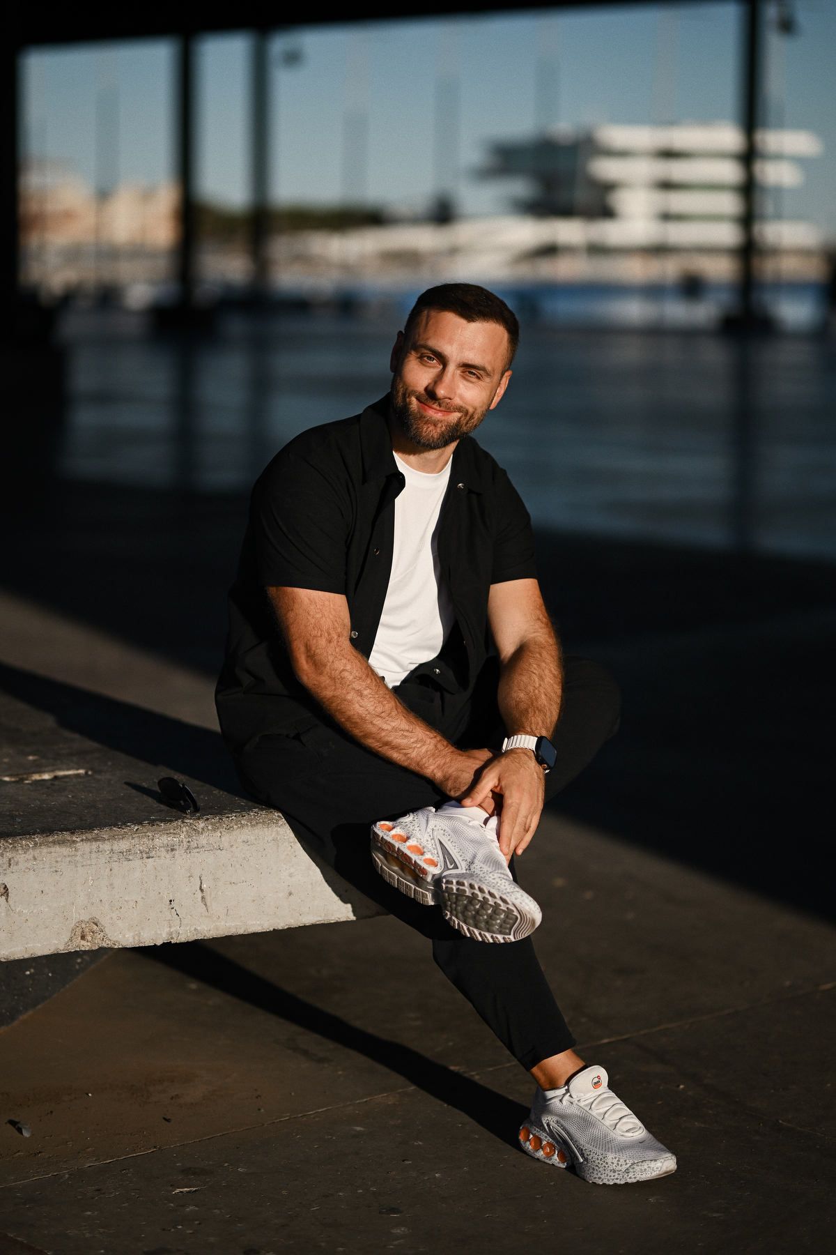 Full-length portrait of a male executive sitting in front of modern corporate and office architecture in Valencia, Spain.