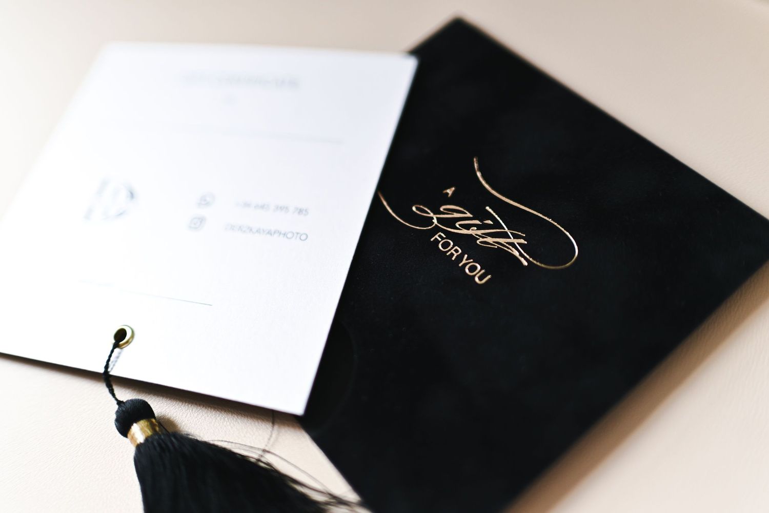 Close-up of a black envelope featuring gold foil lettering A gift for you and a white photoshoot gift card.