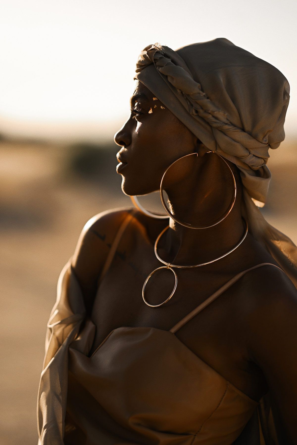 Close-up fashion beauty shot highlighting gold metallic jewelry and professional styling for commercial fashion brands.