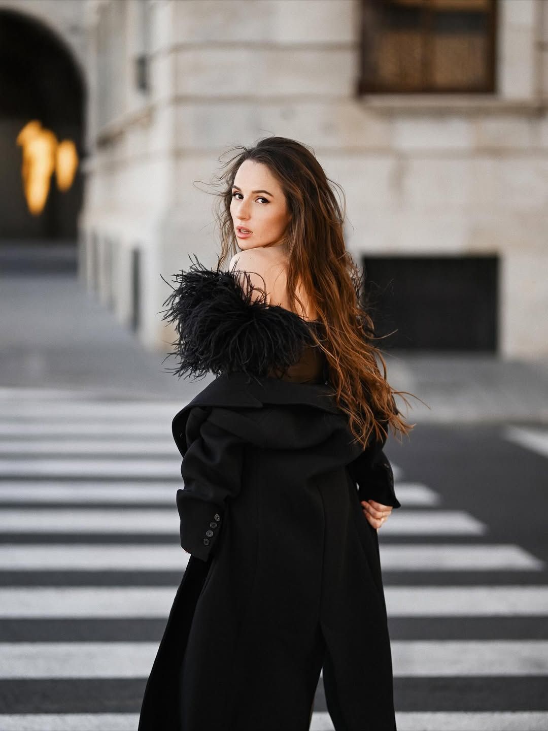 A fashionable model turning around on a city crosswalk, creating a chic editorial look for an urban fashion session.