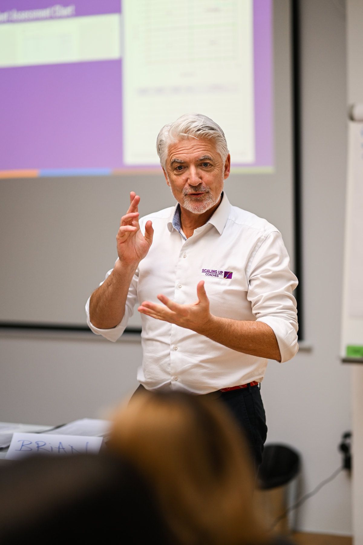 Portrait of a male speaker in a white shirt presenting during a corporate event show program.
