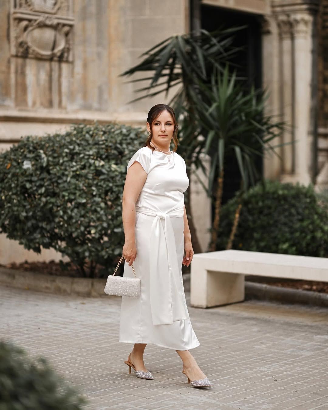 Woman in an elegant white dress walking through a historic Valencia neighborhood during a professional portrait photoshoot