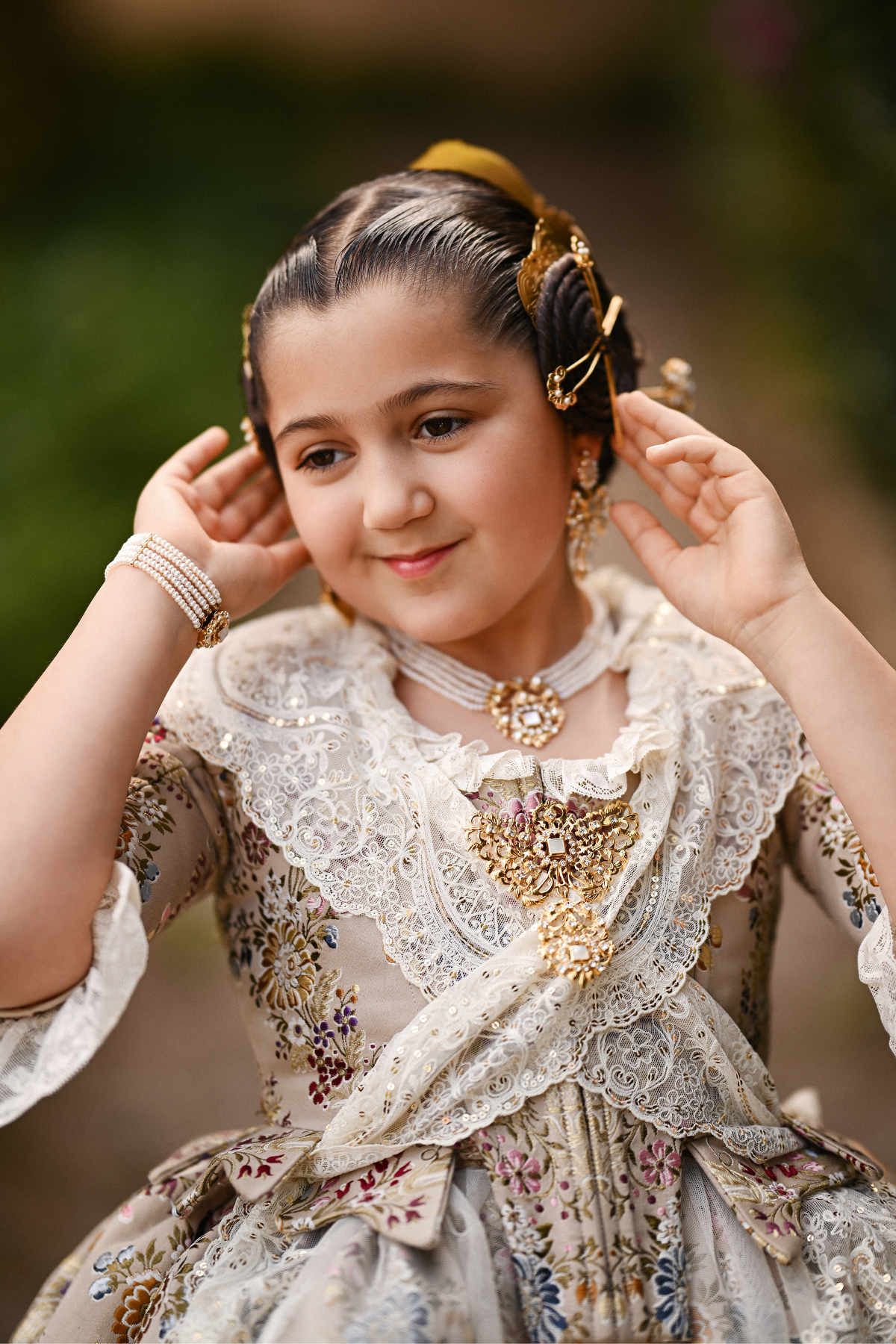 young girl’s traditional Fallera hairstyle featuring peinetas and pearl aderezos jewelry, highlighting the craftsmanship of her manteleta