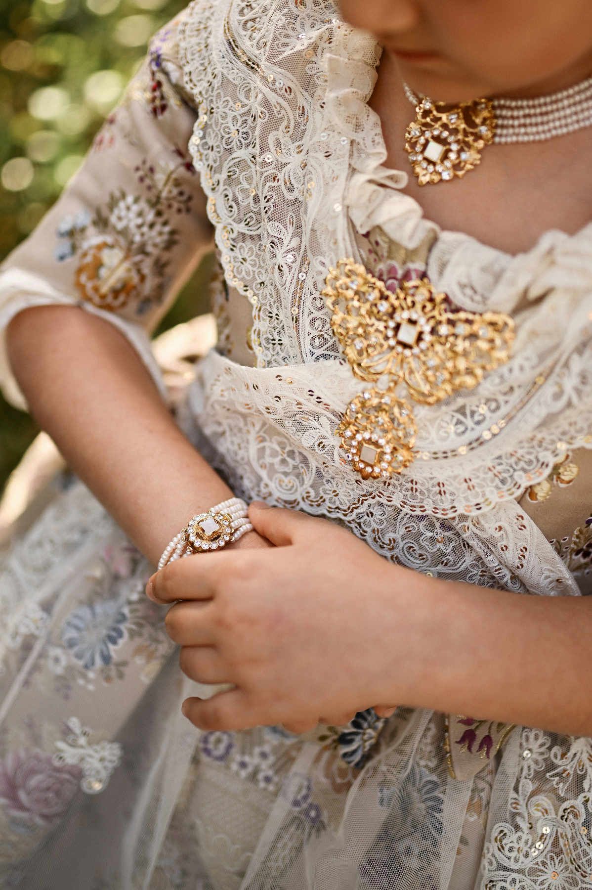 photograph capturing the exquisite craftsmanship of the Fallera jewelry, including the pearl bracelet and ornate brooch on the lace bodice