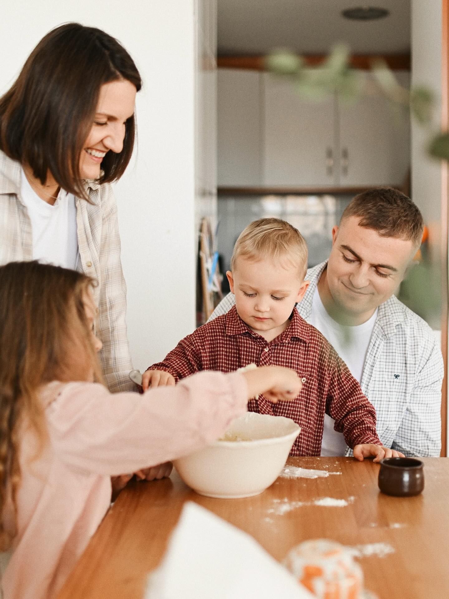A happy family with two young children working together to bake in their home kitchen, capturing a heartwarming and messy activity.