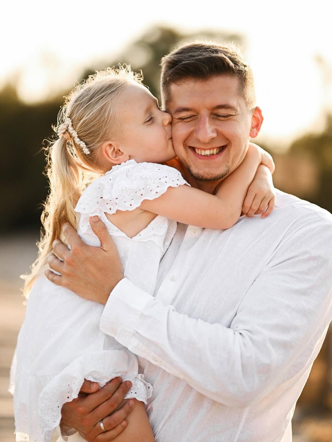 A heartwarming close-up portrait of a father receiving a kiss on the cheek from his daughter in El Saler.
