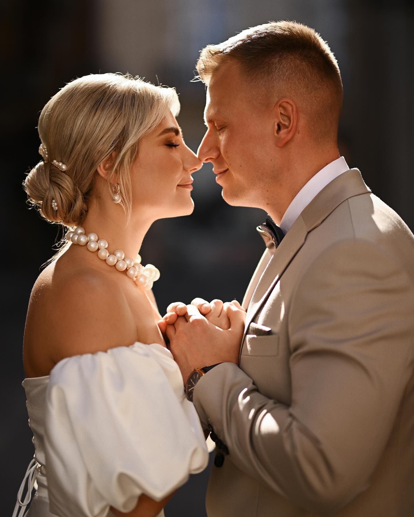 A cinematic close-up of an eloping couple holding hands and leaning in for a kiss in the warm dramatic light of a narrow Valencia street.
