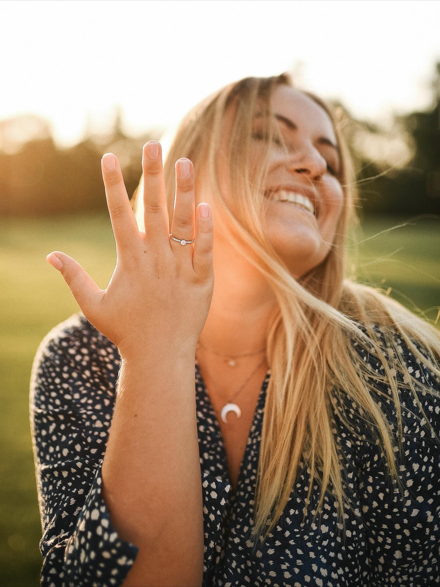 A happy woman showing her engagement ring during a surprise proposal photoshoot in a park in Valencia.