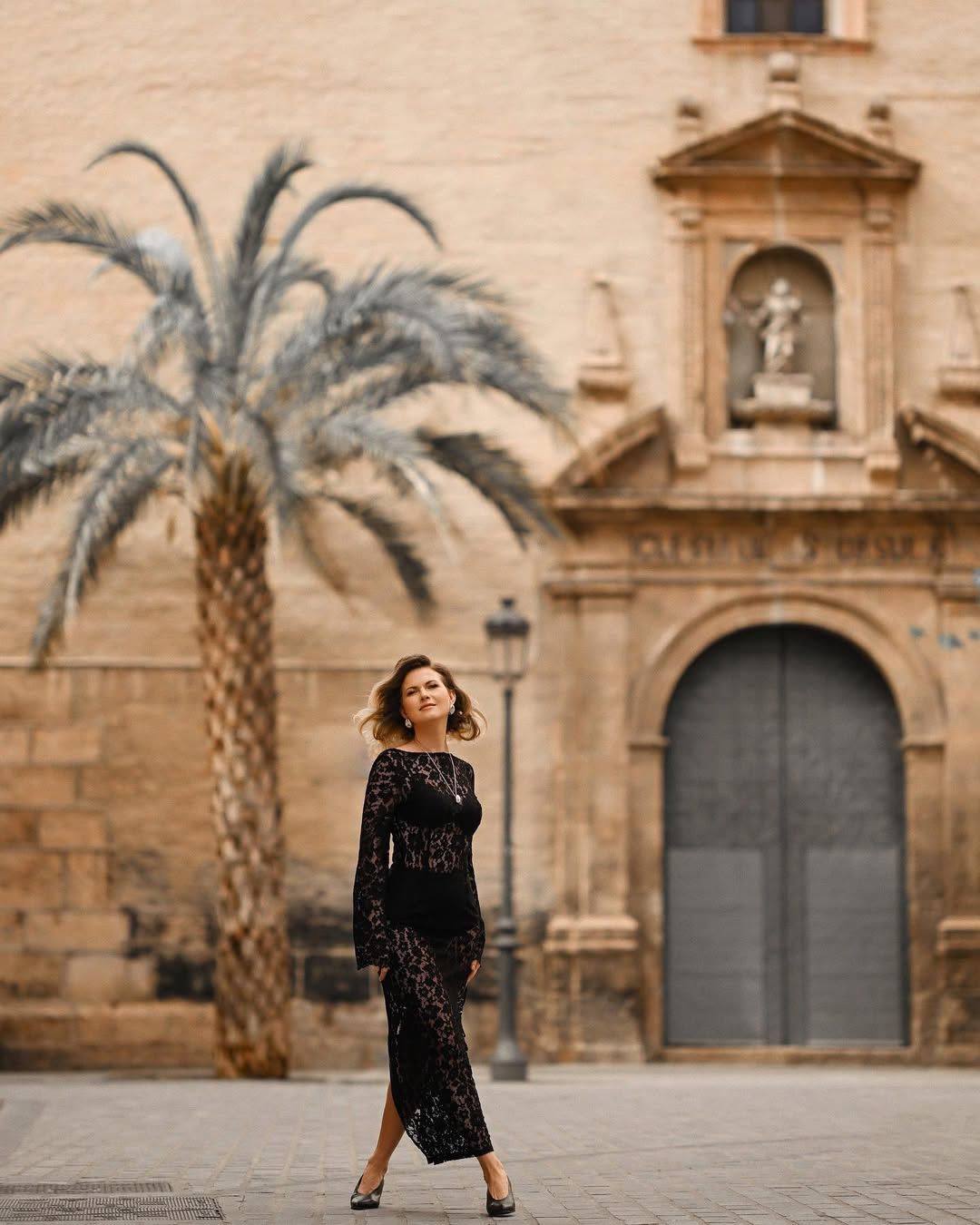 A styled woman walks past a historic Valencia church, capturing a professional editorial look on a city street.