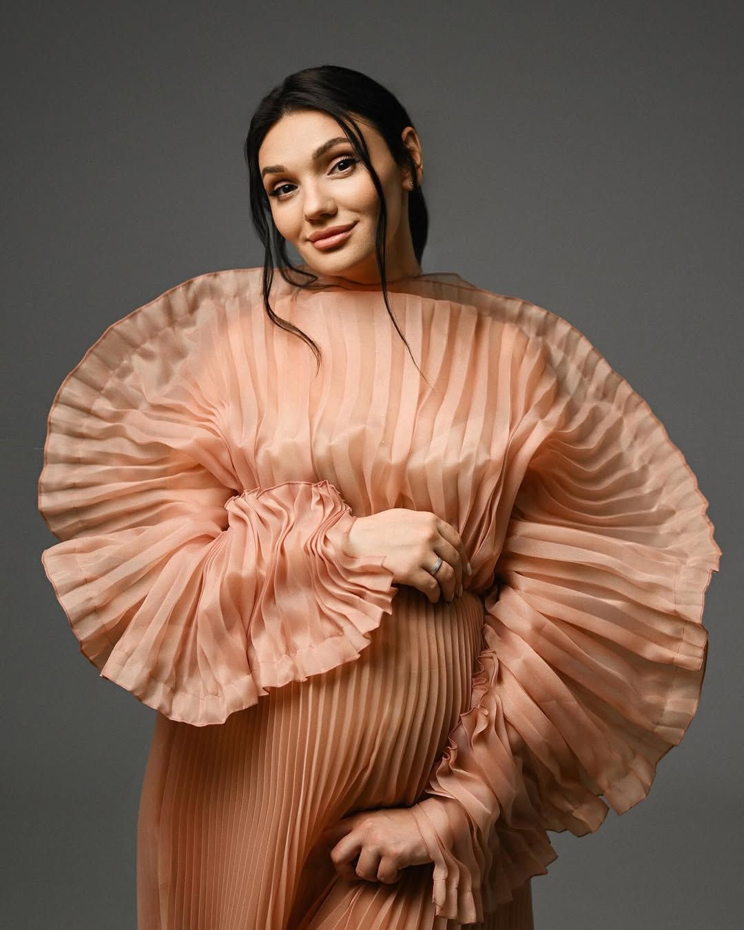 Close-up fine art portrait of an expecting mother in a ruffled peach dress taken in a Valencia maternity studio