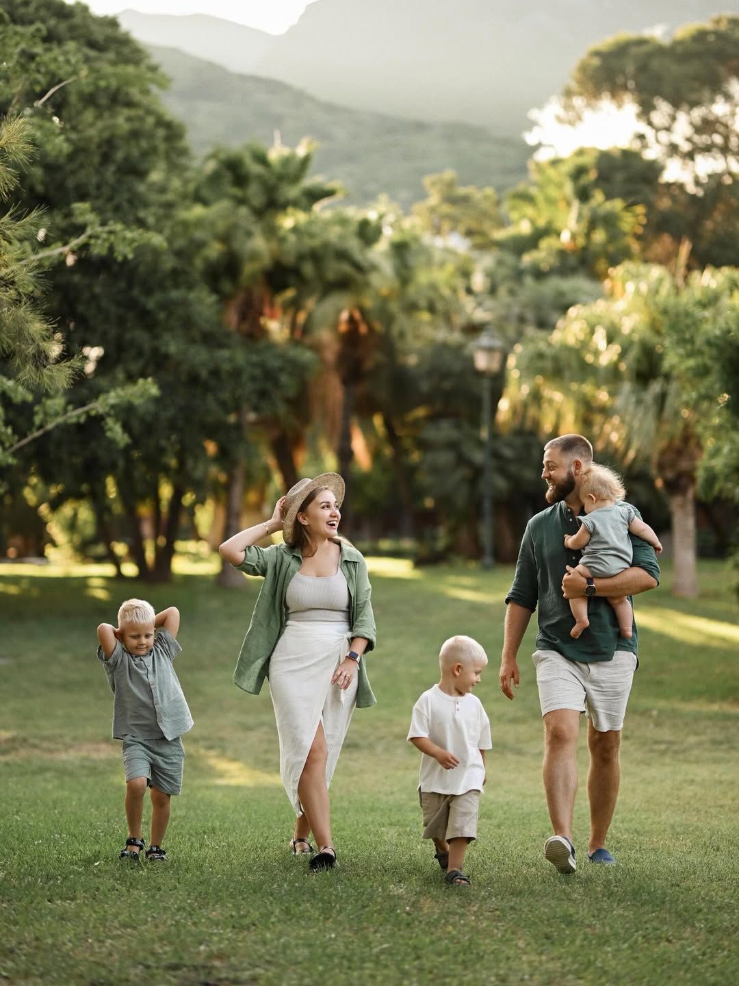 A family of five walking across a lush green lawn in Turia Park, enjoying a casual family photoshoot.