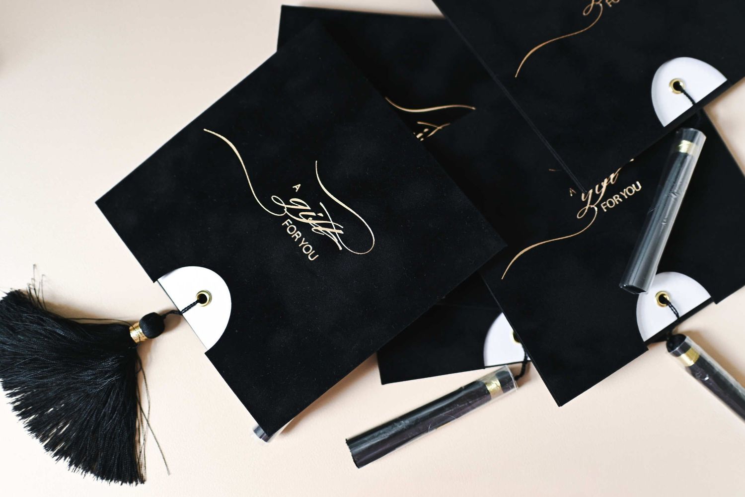 Open printed photography gift certificate on a light background next to a black velvet envelope with a tassel.