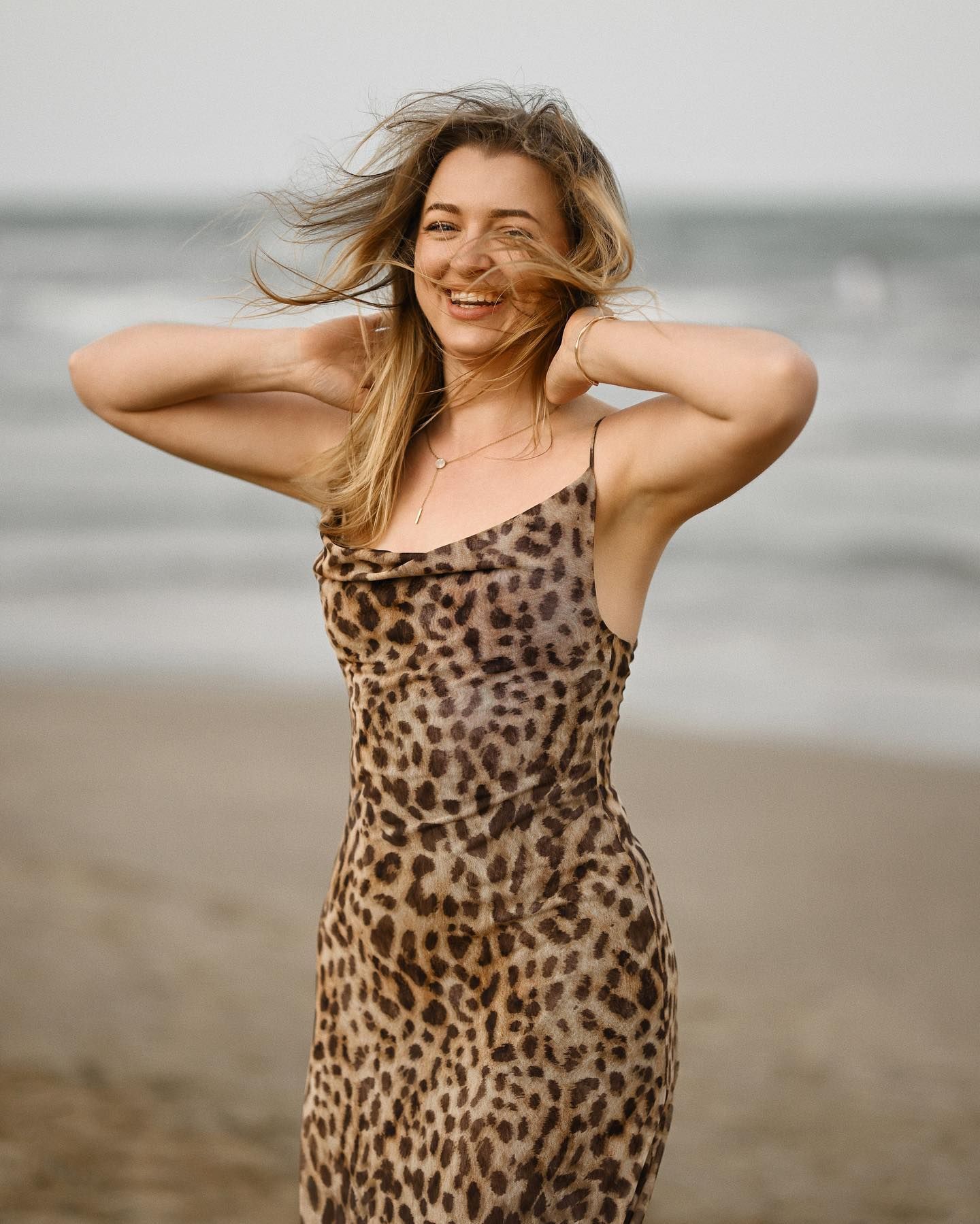 Close-up portrait of a laughing blonde woman with her hair blowing in the wind on a beach in Alicante.
