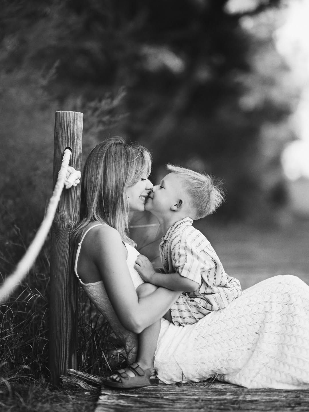 Black and white capture of a mother and son sharing a close, tender moment sitting together on the boardwalk at El Saler.
