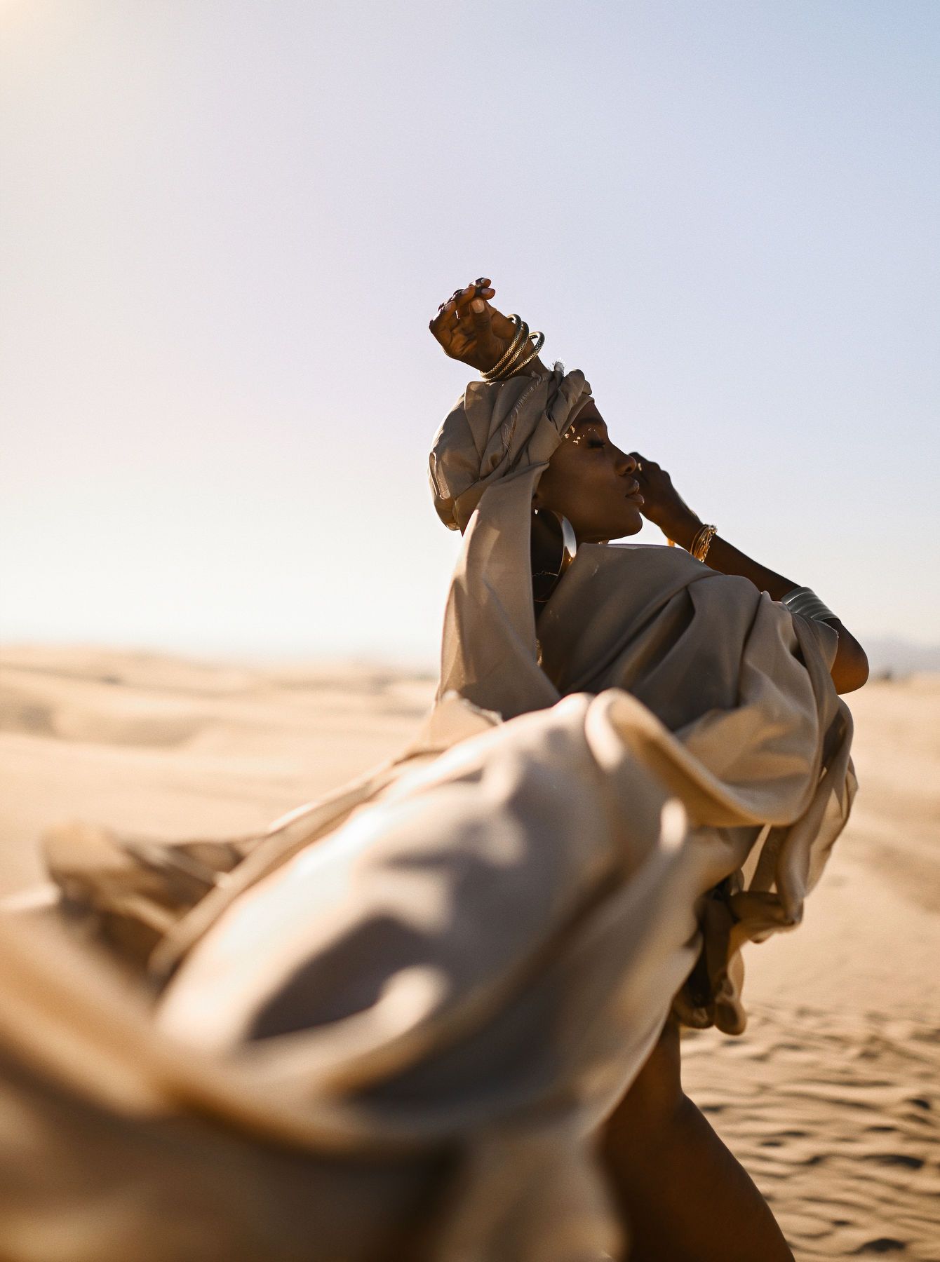 A dynamic fashion editorial shot featuring movement and flowing fabric in a desert environment for commercial campaigns.