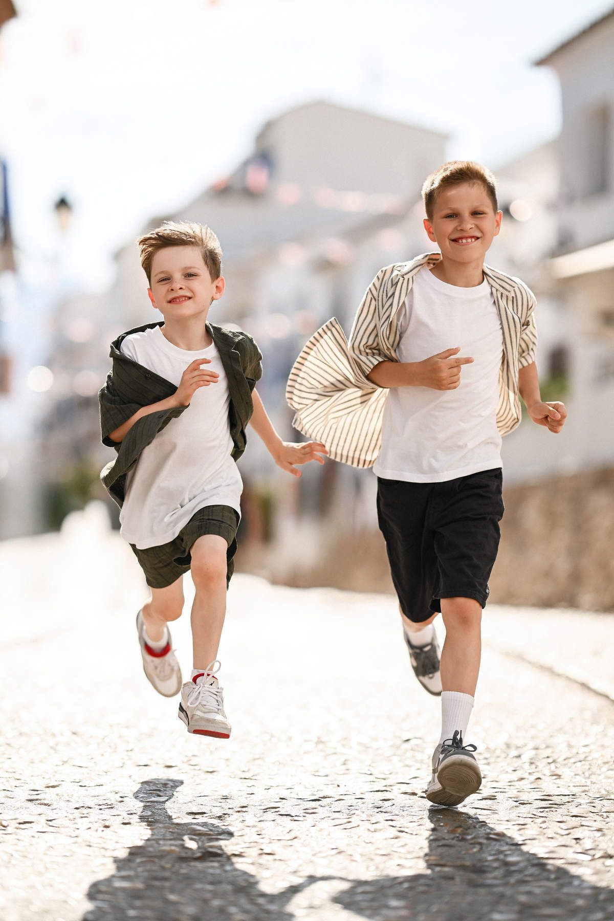 Children running freely on the sunny cobblestone streets of Altea during a relaxed, documentary-style family session.
