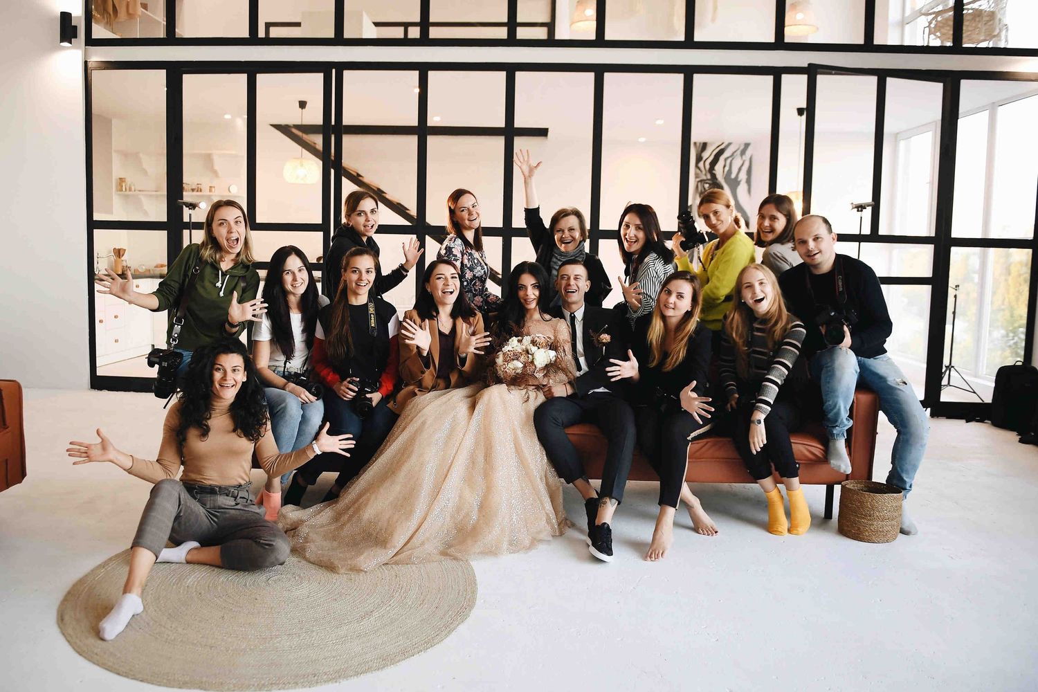 Cheerful group portrait of photography mastermind attendees, mentors, and a model posing together in a modern studio.