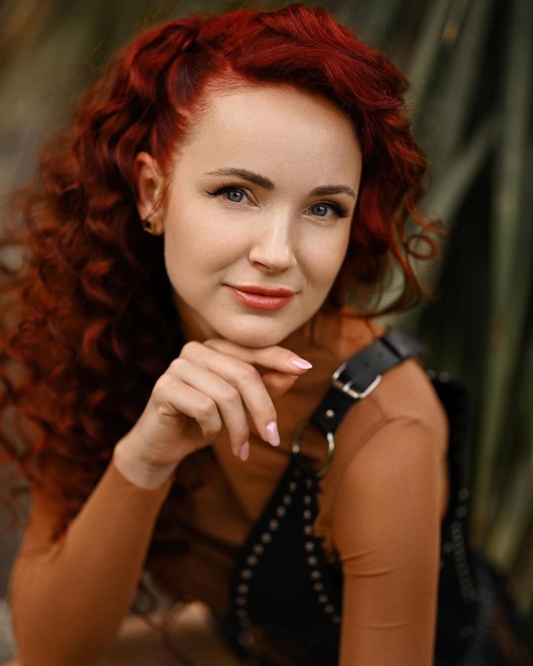 A beautiful close-up portrait of a woman with red hair posing in the Botanical Garden of Valencia.