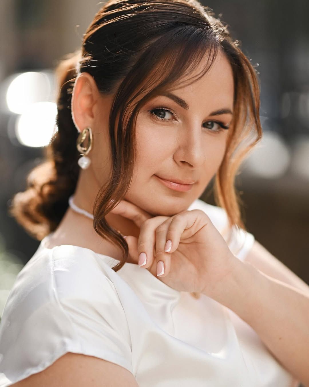 Close-up beauty portrait of a woman wearing pearl earrings and a white dress during a solo photography session in Valencia