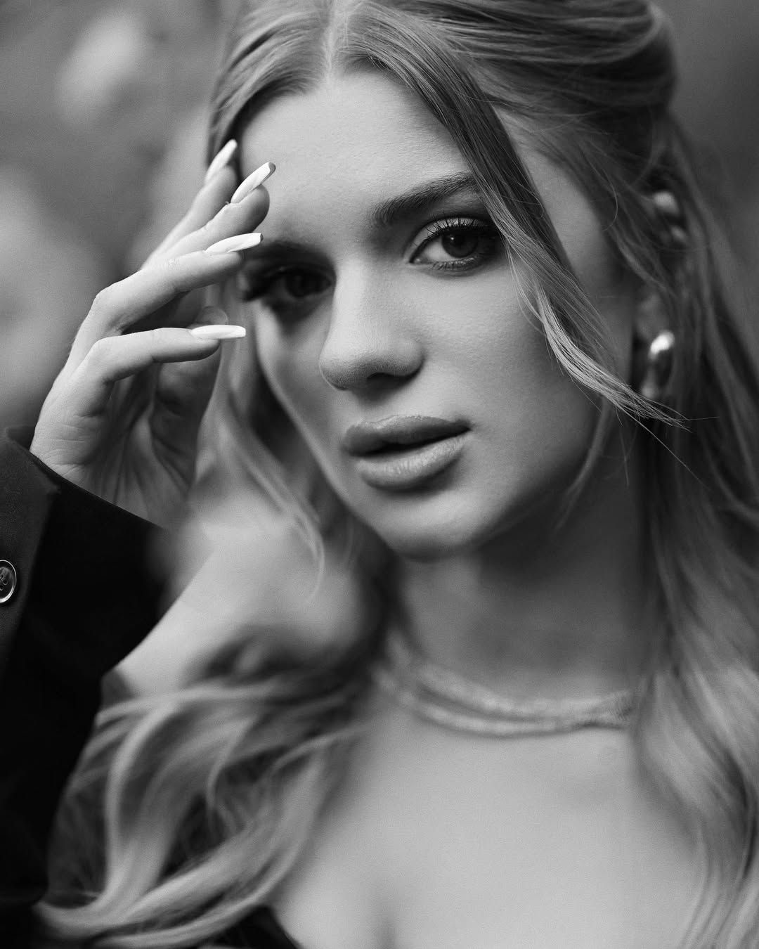 A black and white close-up emotional portrait of a woman looking directly into the camera lens.