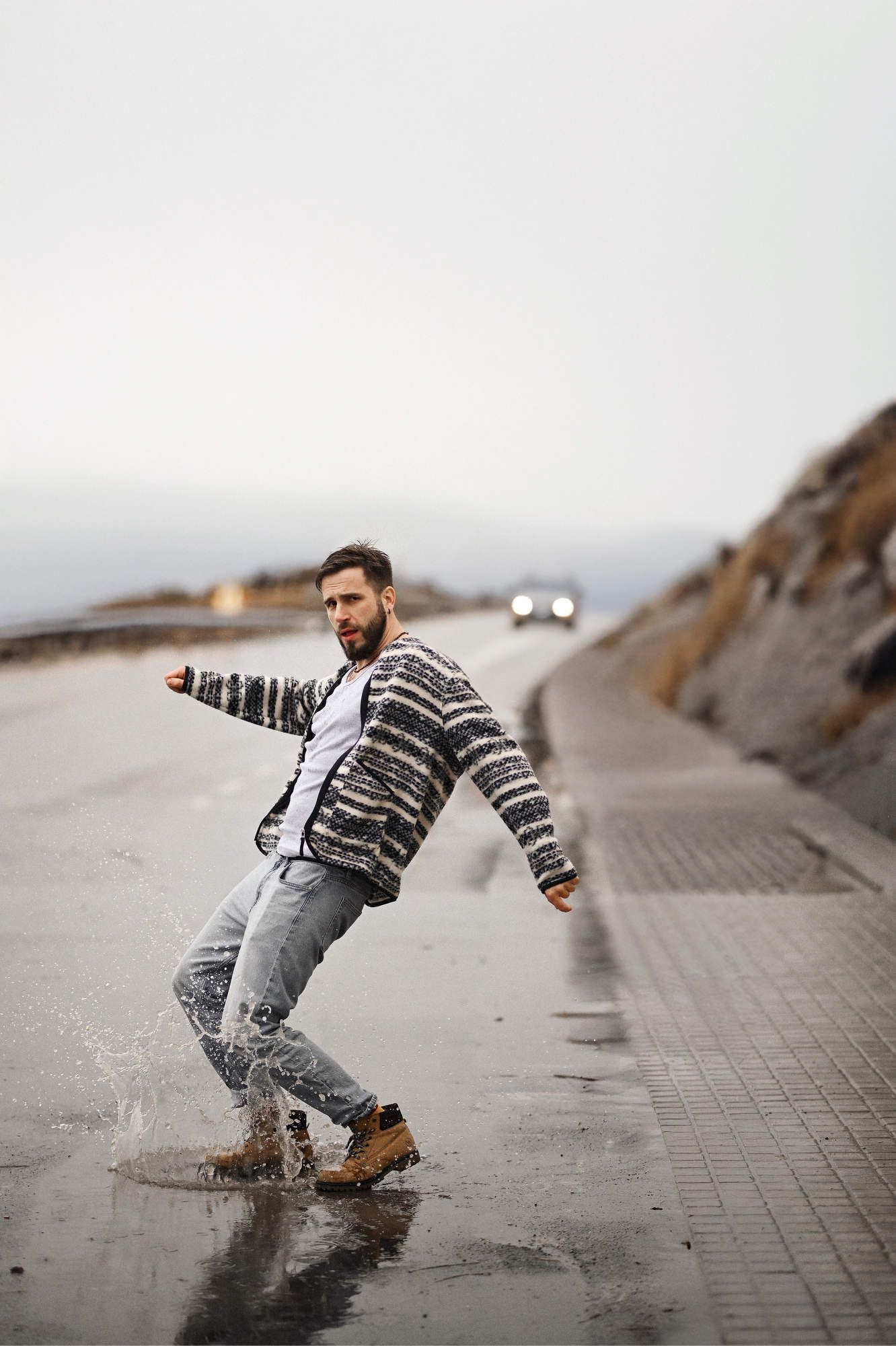 Dynamic action photo of a rugged man splashing a puddle during an outdoor male casual style lifestyle photography session in Valencia.